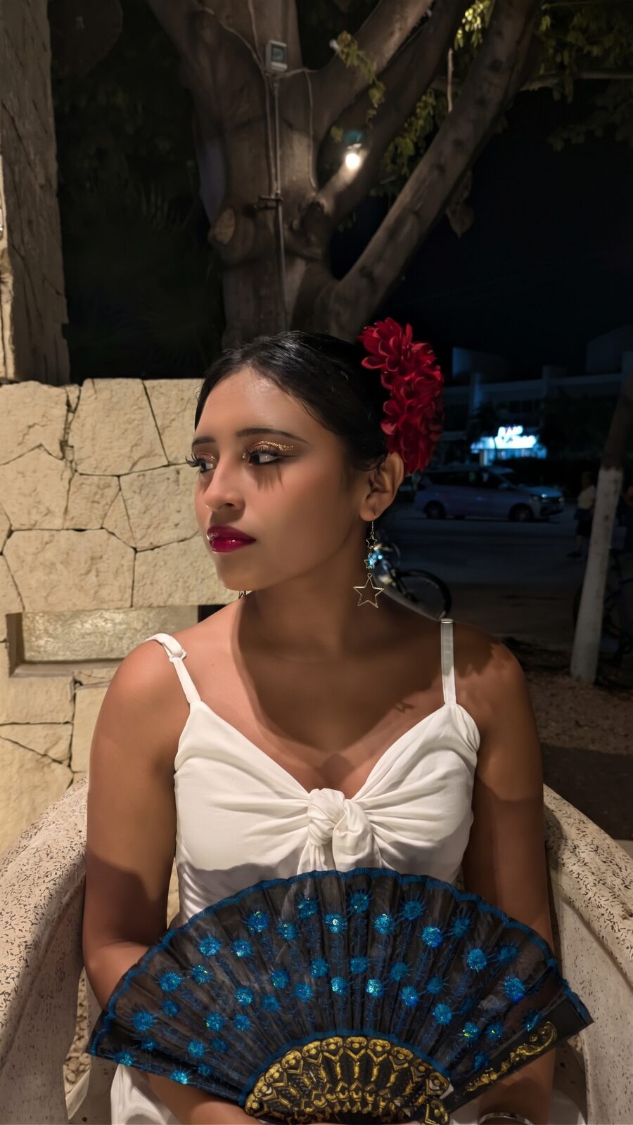 Crista Alejandra con vestido blanco, flor roja en el cabello y un abanico